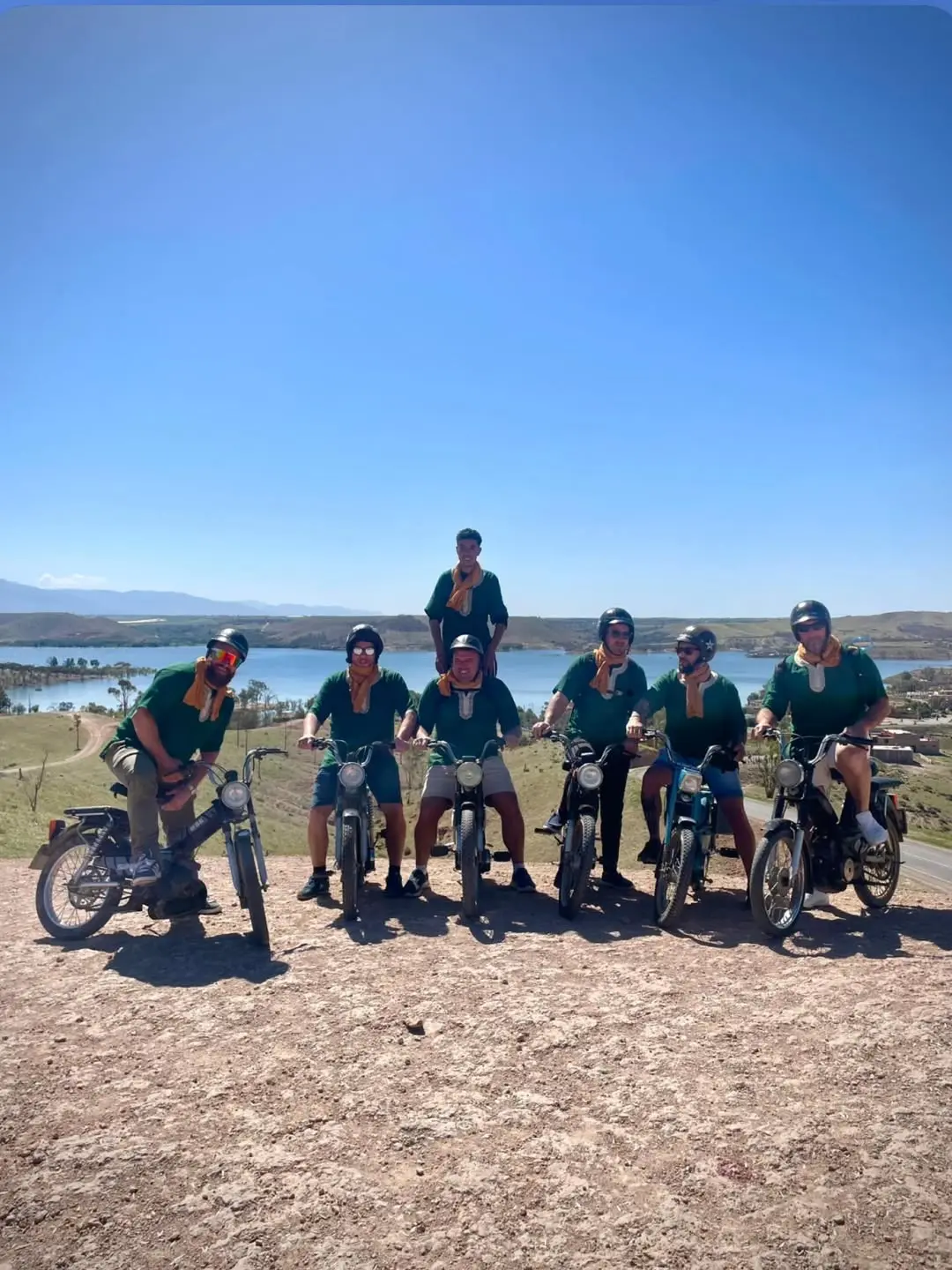 Groupe de participants en mobylette, casque et foulard, devant le lac Lalla Takerkoust