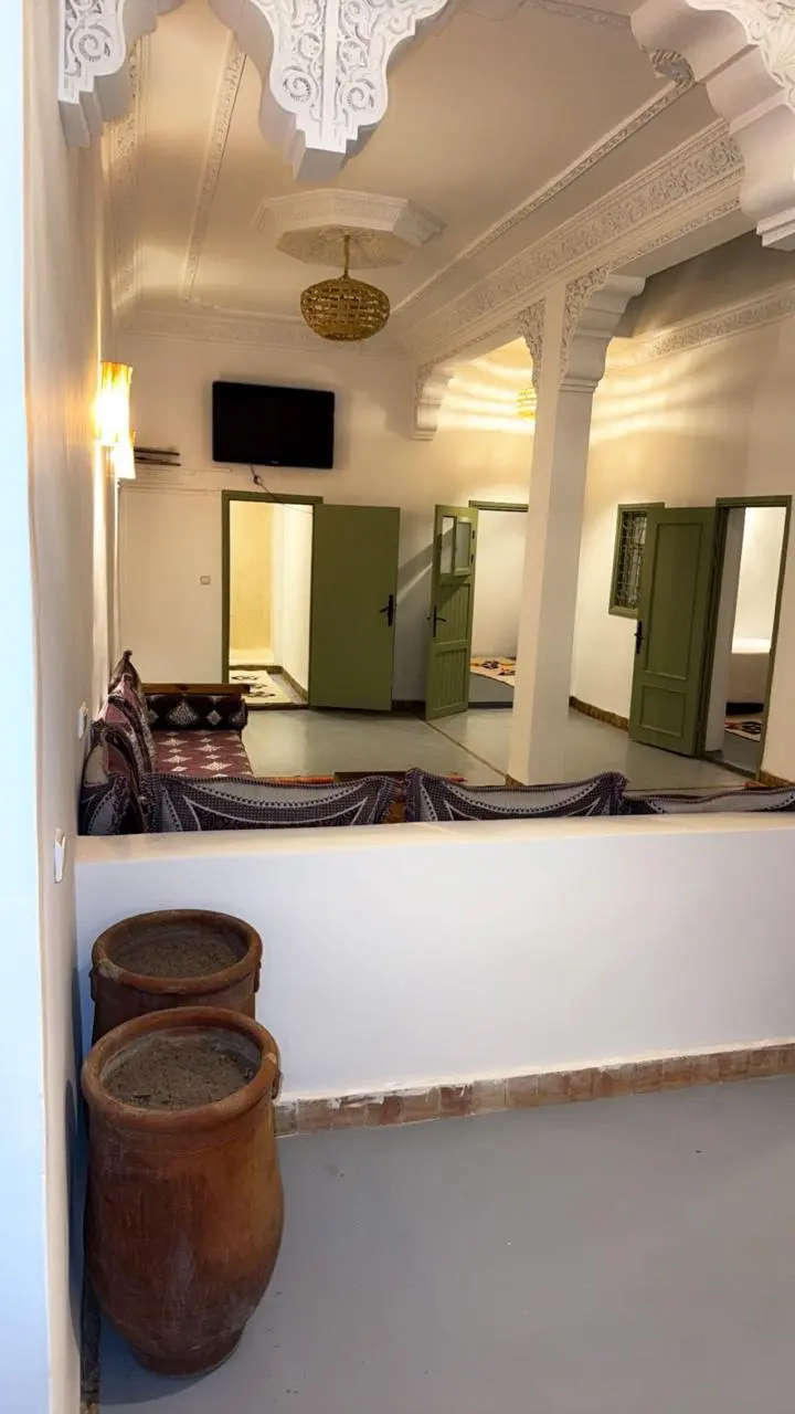 Galerie intérieure de la maison : arches sculptées, portes vertes et jarres en terre cuite
